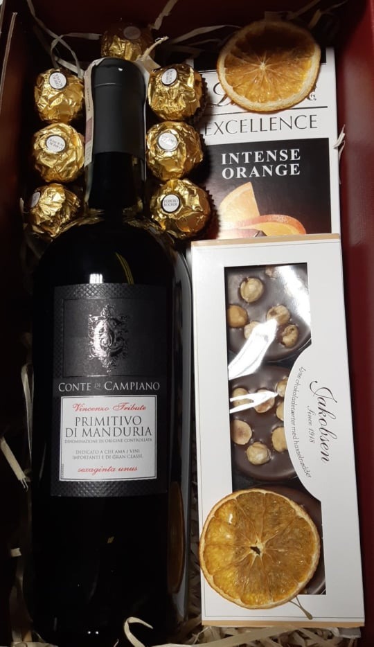 Zestaw upominkowy: butelka czerwonego wina Conte di Campiano Primitivo di Manduria, czekoladki Ferrero Rocher w złotych papierkach, czekolada Jakobsen z orzechami laskowymi i suszone plastry...