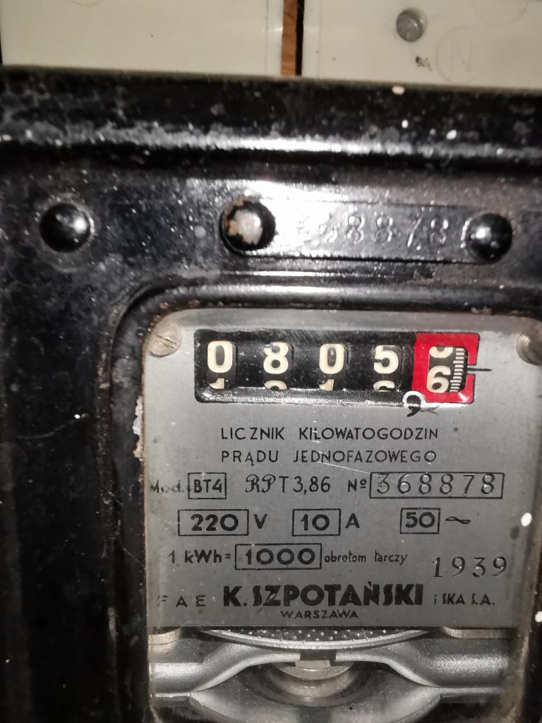Stary, analogowy licznik energii elektrycznej, wyprodukowany w 1939 roku przez FAE K. Szpotański i S-ka S.A. w Warszawie, z widocznym wskazaniem 08056 kWh.