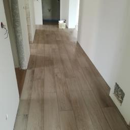 Darioremonty - Korytarz w trakcie wykańczania: ułożona podłoga z paneli imitujących drewno, ściany w trakcie malowania, widoczne niedokończone fragmenty i instalacje elektryczne.