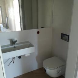 Darioremonty - Nowoczesna łazienka z podwieszaną umywalką nablatową, toaletą w zabudowie i podłogą wyłożoną płytkami imitującymi drewno w jodełkę; widoczne elementy instalacji wodnej pod umywalką.