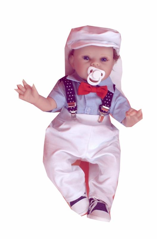 Ubrana lalka niemowlęca w błękitną koszulę, białe spodnie na szelkach w kropki, czerwoną muchę i białą czapkę.