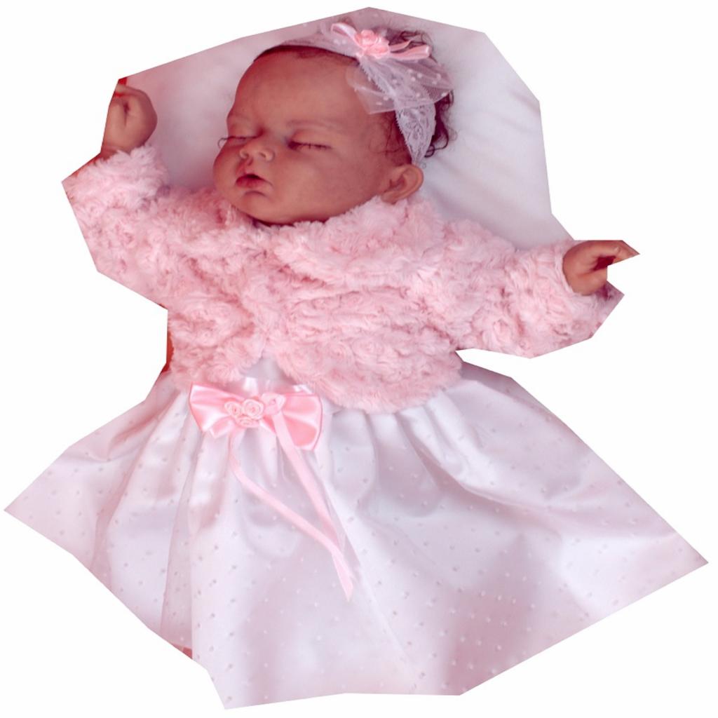 Śpiące niemowlę ubrane w białą sukienkę z różowym bolerkiem i opaską z kokardką.