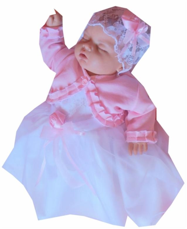 Śpiące niemowlę ubrane w różowo-białą sukienkę z tiulu, bolerko i czepek z koronką i kokardką.