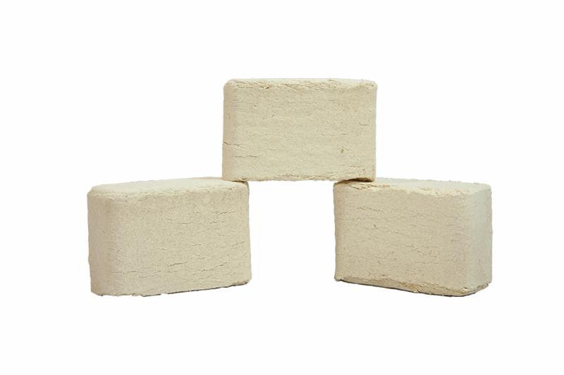 Trzy sprasowane kostki opału ułożone jedna na drugiej, widoczne charakterystyczne włókna i pęknięcia na powierzchni, neutralne tło.