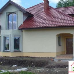 Daneko - Nowo wybudowany dom jednorodzinny z czerwoną dachówką, kremową elewacją i widocznymi śladami prac ziemnych wokół budynku.