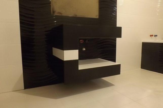 Nowoczesna łazienka z czarno-białymi płytkami o falistej strukturze, wisząca szafka pod umywalkę z białymi elementami, minimalistyczny design.