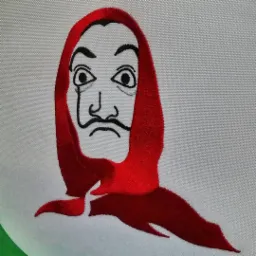 Wyhaftowana maska z serialu La Casa de Papel (Dom z papieru) na jasnoszarym tle, widoczne delikatne cieniowanie czerwonej chusty i szczegóły czarnego konturu twarzy.