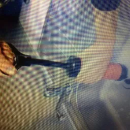 Udrażnianie zlewu za pomocą przepychacza z pomarańczową gumową końcówką, widoczne resztki wody i piany.