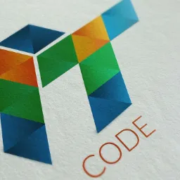 Geometryczny, wielobarwny logotyp firmy IT 'CODE' na teksturowanym papierze.