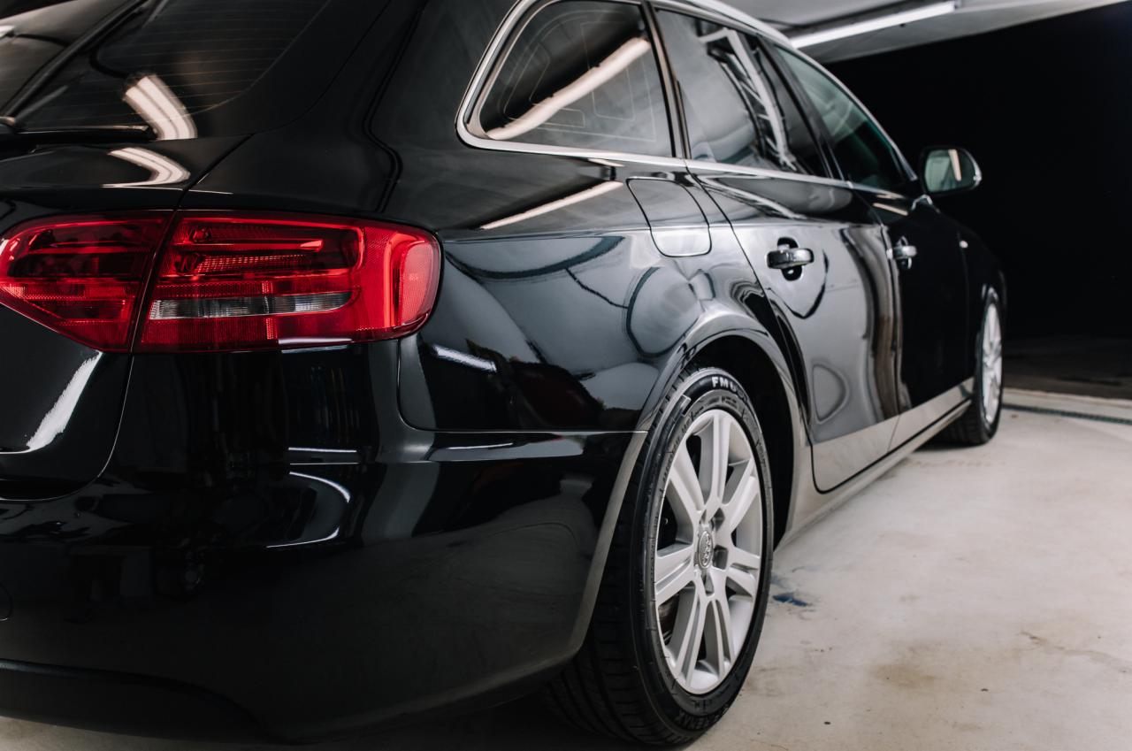 Błyszczący, czarny samochód kombi po umyciu w myjni w Abramowie, widoczny z tyłu, z charakterystycznymi felgami i odbiciami światła na lakierze.