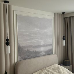 Usługi remontowo-budowlane - Elegancka sypialnia z beżowymi panelami ściennymi, obrazem w ramie nad łóżkiem i wiszącymi lampami. Okno z firankami w tle.