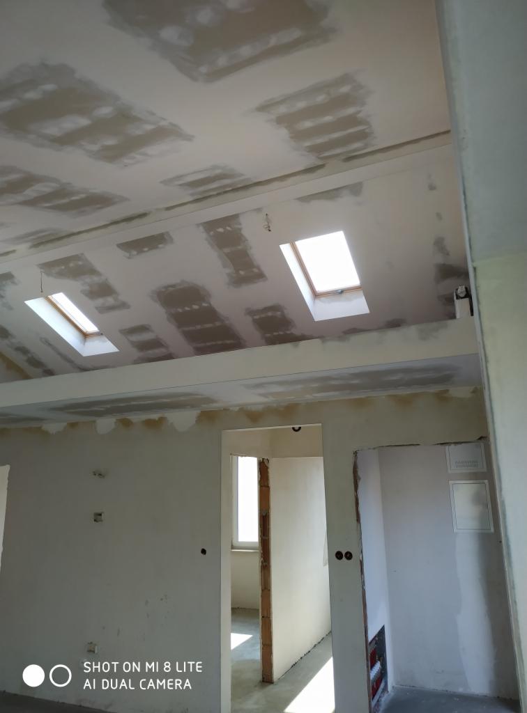 Poddasze w trakcie wykańczania płytami karton-gips z widocznymi oknami dachowymi i niedoskonałościami w szpachlowaniu.