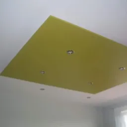 Fragment sufitu z wbudowanymi punktowymi lampami w kwadratowym panelu w odcieniu oliwkowym, otoczonym białym sufitem.