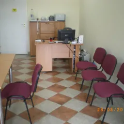 Wnętrze biura w Pile z biurkami, krzesłami dla klientów i podłogą w szachownicę, oświetlone światłem dziennym.