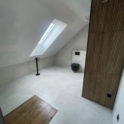Grzegorz Skrabalak - Nowoczesna łazienka na poddaszu z oknem dachowym, czarną armaturą i drewnianą ścianą. Minimalistyczny design, jasne płytki podłogowe, skosy.