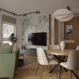 5828 Architektura Wnętrz Mariusz Czarnota - Nowoczesny salon z jadalnią, zielona sofa, okrągły drewniany stół z beżowymi krzesłami na czarnych nogach, ściana z tapetą w szkicowe kwiaty i drewnianymi lamelami, designerska lampa wisząca.