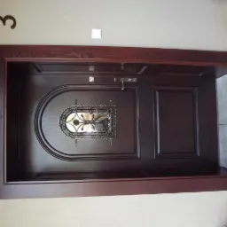 Ciemnobrązowe drzwi wejściowe z ozdobnym, metalowym wizjerem, osadzone w drewnianej ramie, z numerem domu '3' widocznym nad nimi.