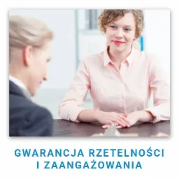 Uśmiechnięta kobieta w różowej koszuli siedzi przy biurku podczas rozmowy z rekruterem, na stole leży clipboard.