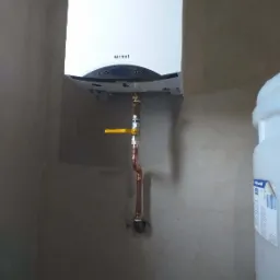 Biały wiszący kocioł gazowy marki Termet z podłączeniem miedzianymi rurami i żółtym zaworem, zamontowany na surowej ścianie.