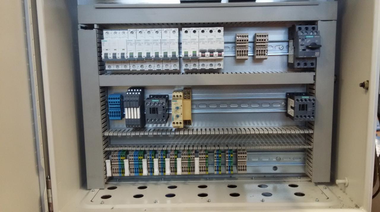 Otwarta szafa sterownicza z zamontowanymi bezpiecznikami, stycznikami i listwami zaciskowymi firmy Siemens.