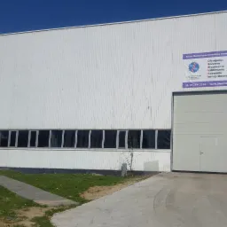 Budynek Zakładu Mechaniczno-Remontowego Energetyki z ofertą usług: toczenie, frezowanie, szlifowanie, spawanie i usługi ślusarskie, widoczny plakat reklamowy z numerem telefonu i adresem strony...