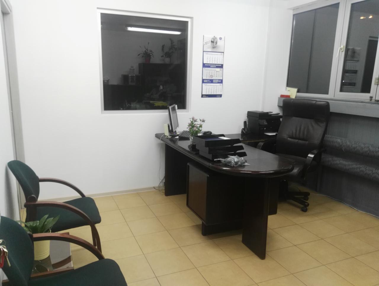 Biuro z biurkiem, krzesłami i kalendarzem na ścianie, widok z perspektywy osoby stojącej w pomieszczeniu.