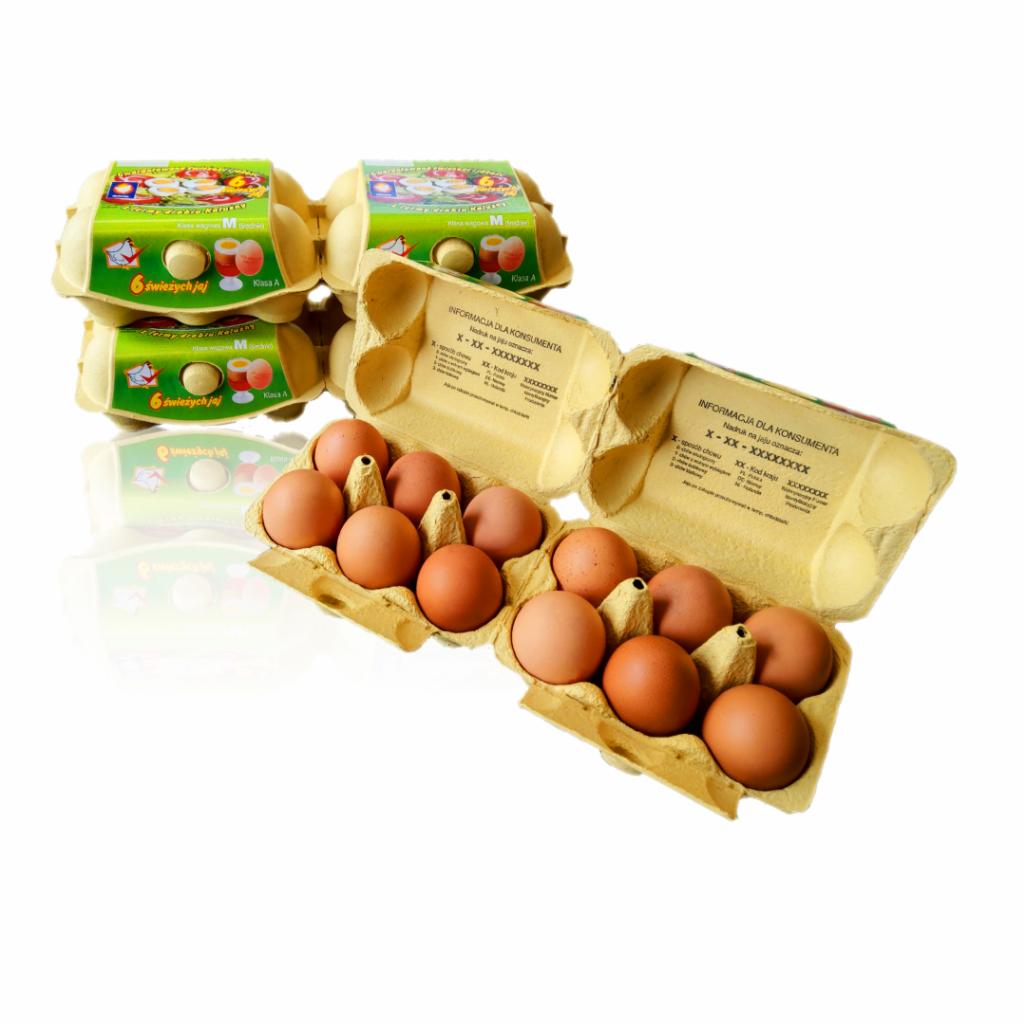 Otwarta wytłaczanka z brązowymi produktami spożywczymi, obok zamknięte opakowania z zieloną etykietą, na białym tle.