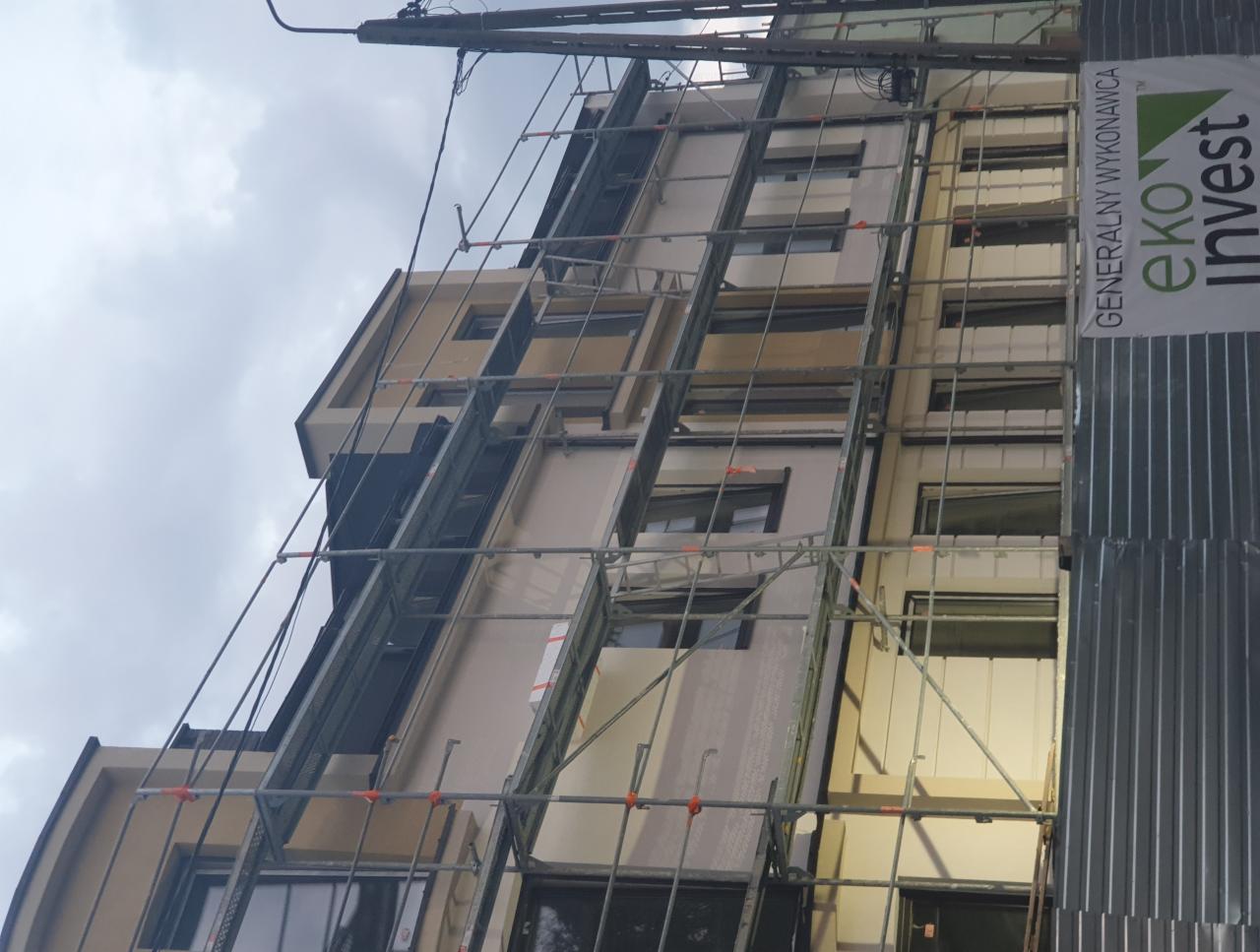 Budynek w Piasecznie w trakcie budowy, otoczony rusztowaniami, z widocznym banerem firmy Eko Invest.