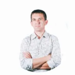 Mężczyzna w koszuli we wzory, z założonymi rękami, na jasnym tle. Portret.