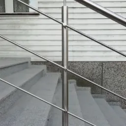 Zewnętrzne schody granitowe z prostą, metalową poręczą z rurek, widoczne elementy elewacji budynku.
