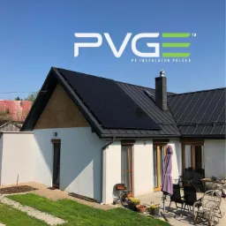 Dom jednorodzinny z czarnymi panelami słonecznymi na dachu, widoczny pod logo firmy PVGE PV Instalator Polska na tle błękitnego nieba.