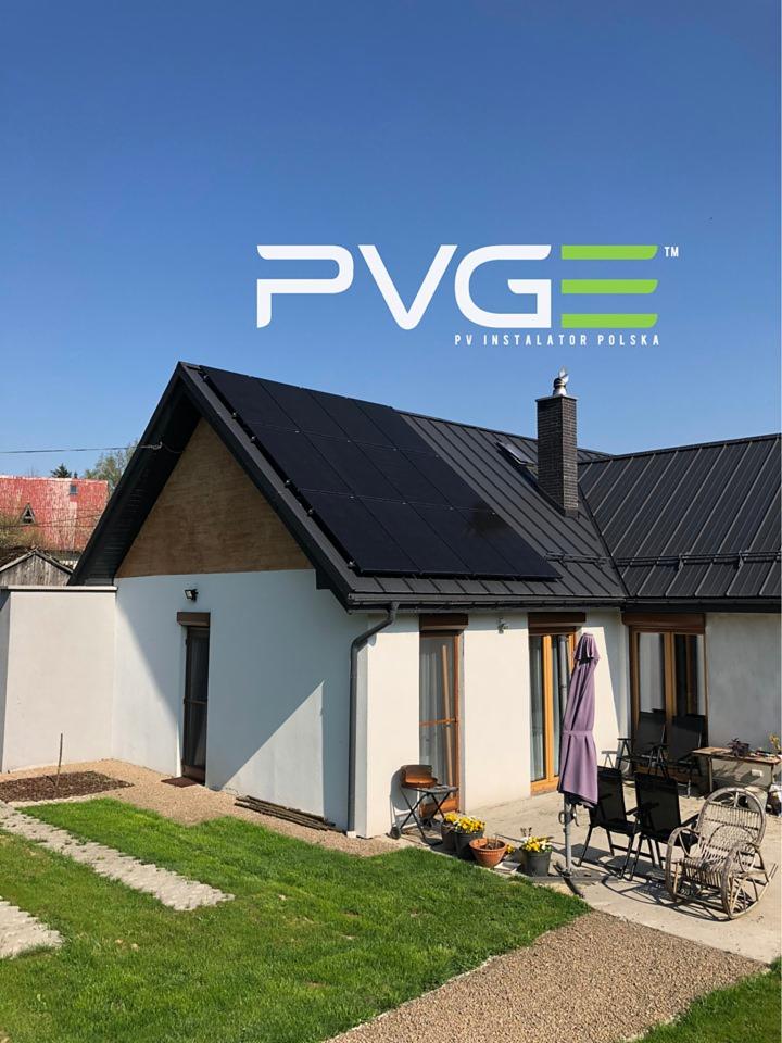 Dom jednorodzinny z czarnymi panelami słonecznymi na dachu, widoczny pod logo firmy PVGE PV Instalator Polska na tle błękitnego nieba.