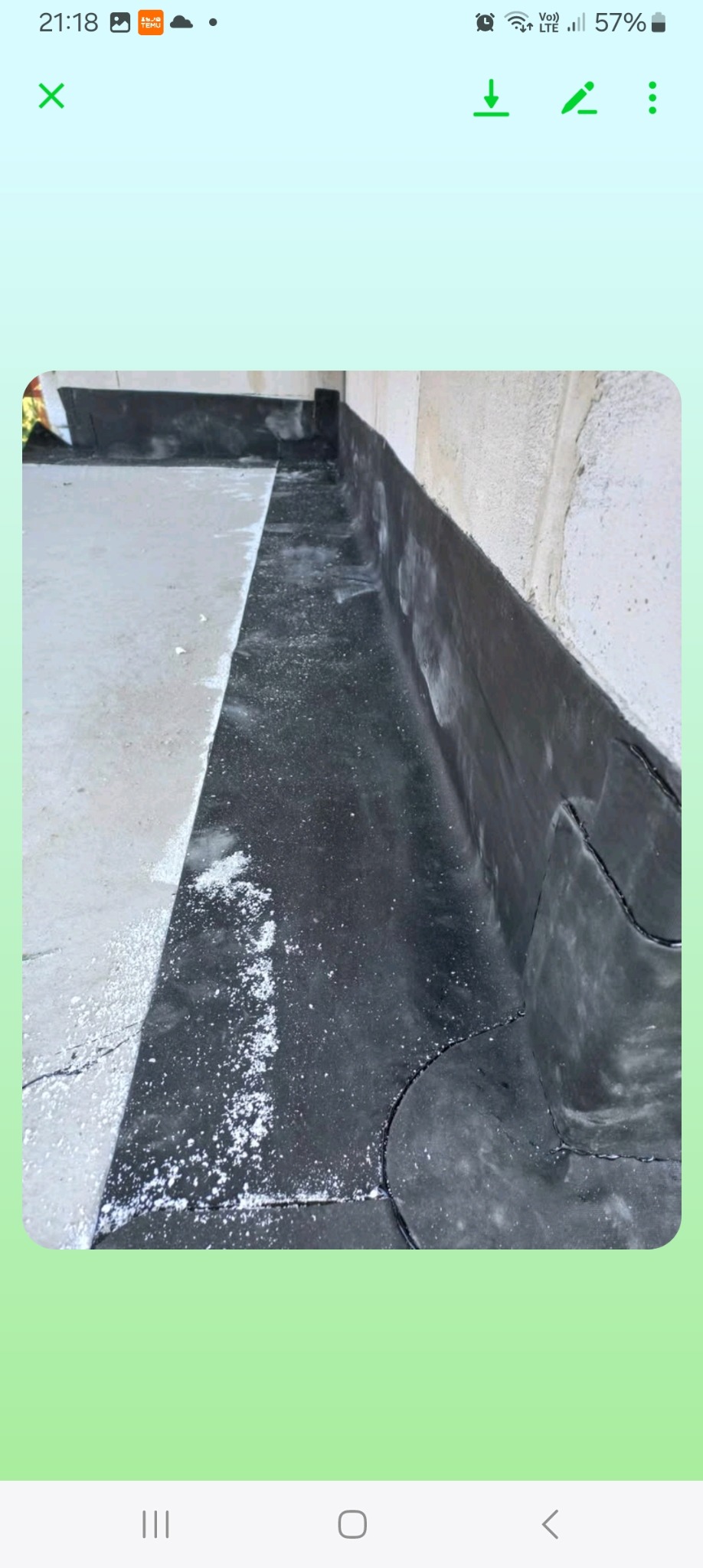 Szczegółowe ujęcie izolacji przeciwwodnej z papy na fundamencie budynku, widoczne łączenia i resztki materiału izolacyjnego.