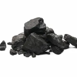 Góra brył czarnego węgla kamiennego o nieregularnych kształtach, oświetlona z góry, na jednolitym białym tle.