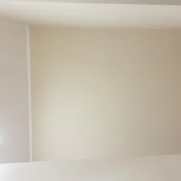 Wykończone wnętrze: kremowa ściana, drewniana ściana z poziomych desek i sufit z wbudowanym oświetleniem.