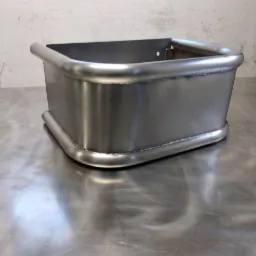 Metalowa konstrukcja spawana z rur o zaokrąglonych narożnikach, leżąca na metalowym blacie, widoczne ślady spawania