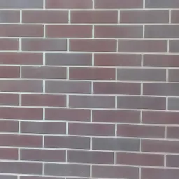 Elewacja z cegły klinkierowej w odcieniach czerwieni i szarości z jasną fugą, ułożona w regularny wzór.