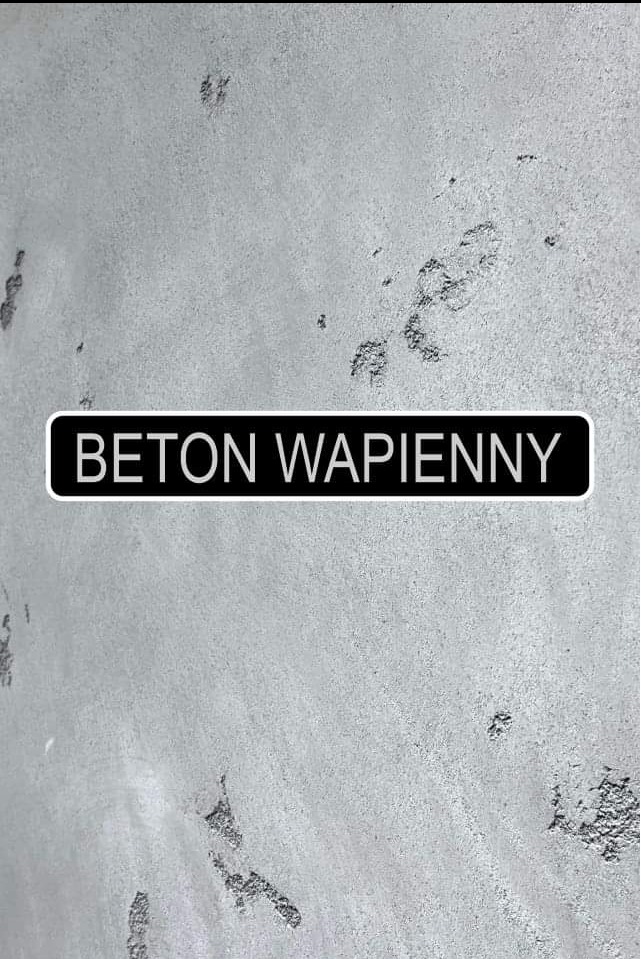 Tekstura ściany pokrytej betonem wapiennym, z widoczną tabliczką informacyjną z nazwą materiału.