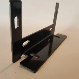 Czarny, metalowy wspornik kątowy z otworami, ustawiony pod kątem na jasnym tle, widoczne refleksy światła na błyszczącej powierzchni.