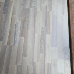 Jasne, drewniane panele podłogowe, świeżo położone w Tylmanowej, z widocznym fragmentem progu.