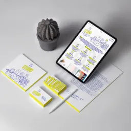 Prezentacja identyfikacji wizualnej firmy na tablecie, wizytówkach i papierze firmowym, obok doniczki z kaktusem i rysika, w minimalistycznym stylu.