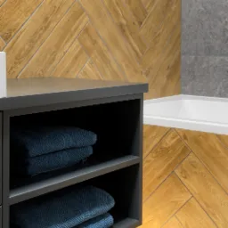 Wykończona łazienka z drewnopodobną glazurą ułożoną w jodełkę, szarą szafką z ręcznikami i fragmentem wanny. Nowoczesne wzornictwo i dbałość o detale.