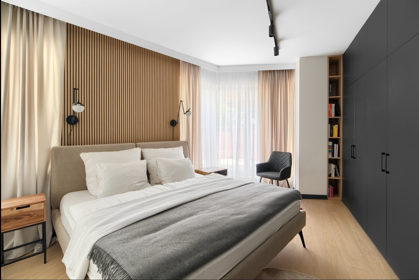 Nowoczesna sypialnia z drewnianą ścianą z lameli, szarą pościelą i czarnymi lampami ściennymi. Minimalistyczny design, jasne wnętrze.