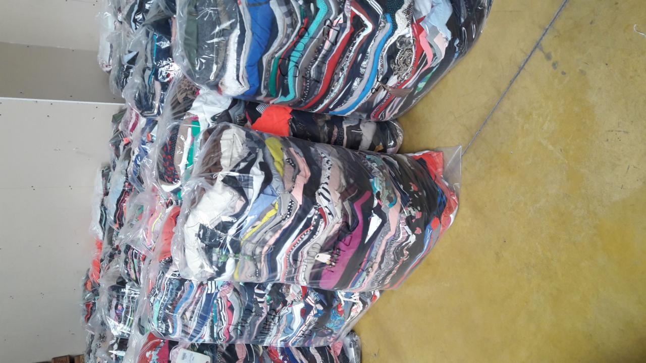 Bale odzieży używanej zapakowane w folię, przygotowane do transportu w Boxmeer, widoczne różnorodne wzory i kolory ubrań.