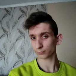 Portret młodego copywritera z Bobrowej w neonowej bluzie na tle tapety w liście. Wyraz twarzy: lekki uśmiech, patrzący w obiektyw, naturalne oświetlenie.