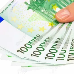 Dłoń trzymająca wachlarz pięciu banknotów 100 euro, lekko rozłożonych, z widocznymi znakami wodnymi i elementami zabezpieczeń.