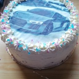 Mąż i Żona - Okrągły tort z białym kremem i posypką, dekorowany jadalnym nadrukiem przedstawiającym sportowy samochód.