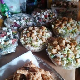 Mąż i Żona - Przygotowane sałatki greckie i Cezar w przezroczystych miskach oraz smażone kawałki kurczaka na tacy, gotowe do serwowania.