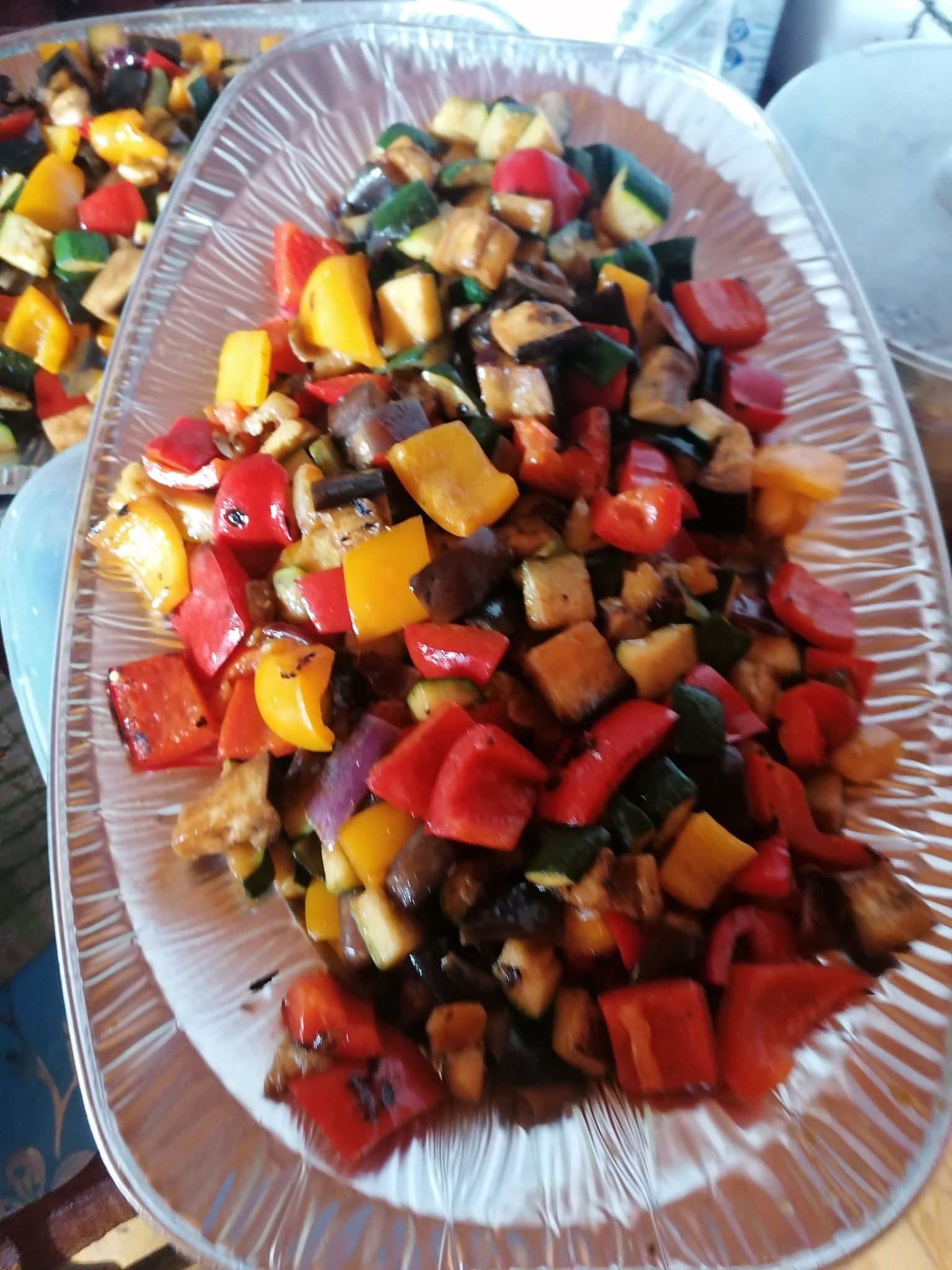 Dwa półmiski z grillowanymi warzywami: papryka czerwona i żółta, cukinia i bakłażan, pokrojone w kostkę, na przezroczystych półmiskach.