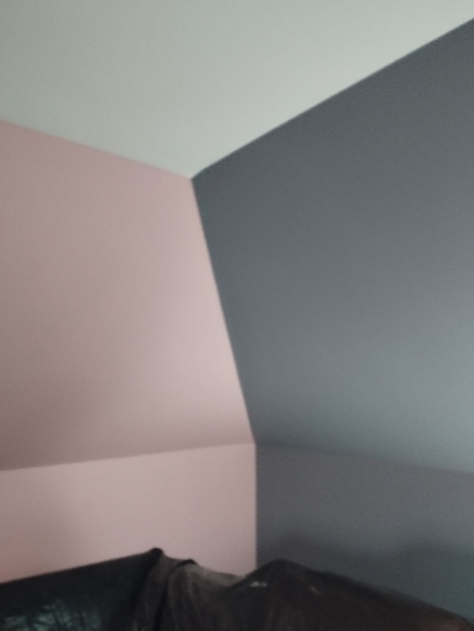 Ściana w pokoju pomalowana na dwa kolory: różowy i szary. Widoczny fragment sufitu. Ujęcie z dołu podkreśla geometrię pomieszczenia.